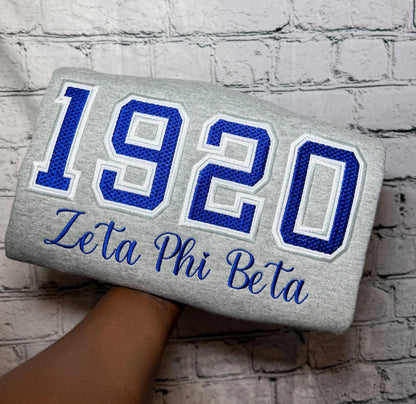 Gray sweatshirt with blue-and-white 1920 Zeta Phi Beta waffle-knit appliqué and embroidered script