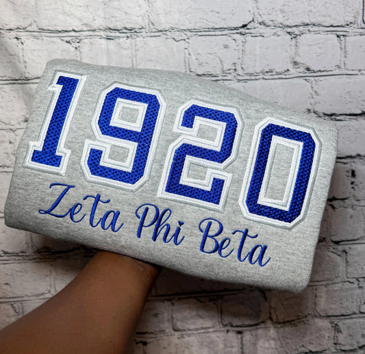 Gray sweatshirt with blue-and-white 1920 Zeta Phi Beta waffle-knit appliqué and embroidered script
