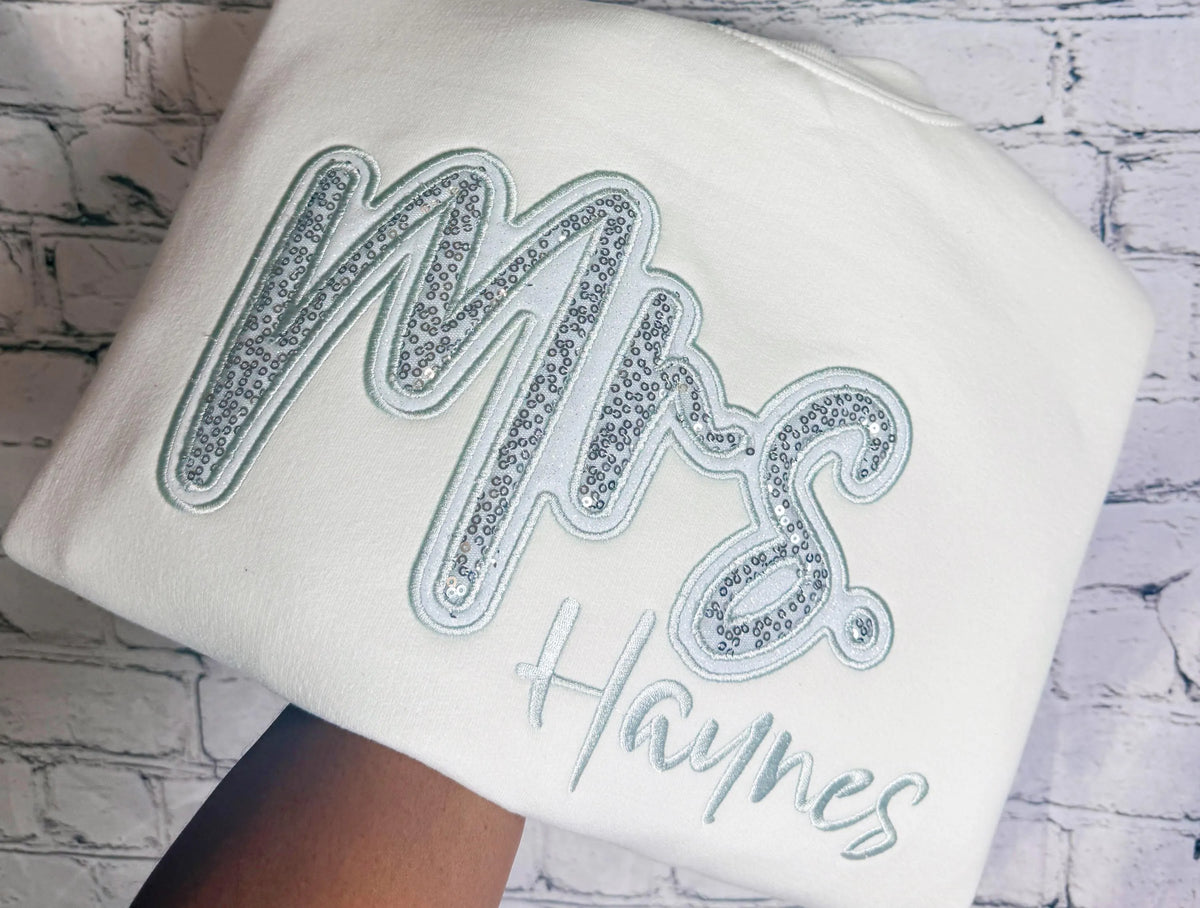 White crewneck with silver sequin Mrs. appliqué and personalized Haynes embroidery