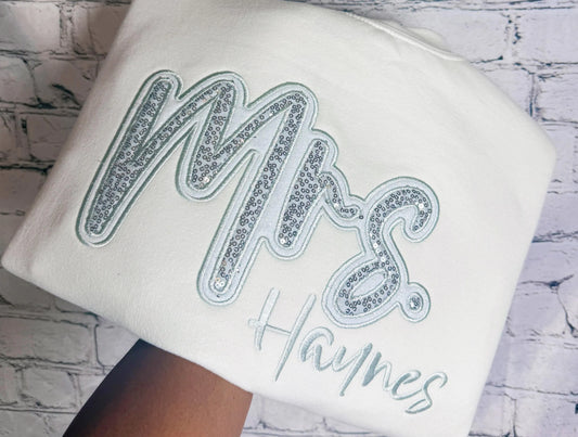 White crewneck with silver sequin Mrs. appliqué and personalized Haynes embroidery